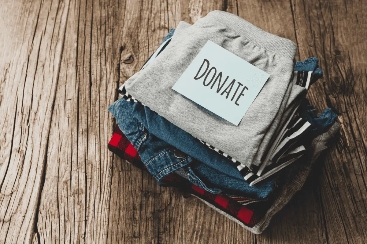 a stack of clothes with a donate sign - best decluttering strategy